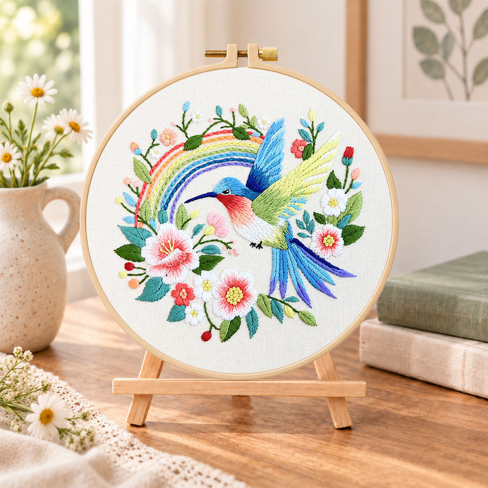 Hummingbird with rainbow embroidery kit finished hoop displayed on a wooden stand as cosy tabletop decor