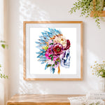 Finished indian feather and flower skull cross stitch artwork displayed