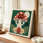 Jack‑o‑lantern mushroom punch needle artwork displayed on a table