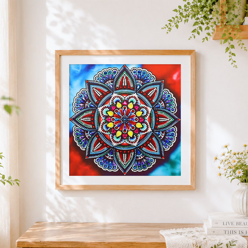 Finished jewel tone red and blue mandala cross stitch artwork displayed