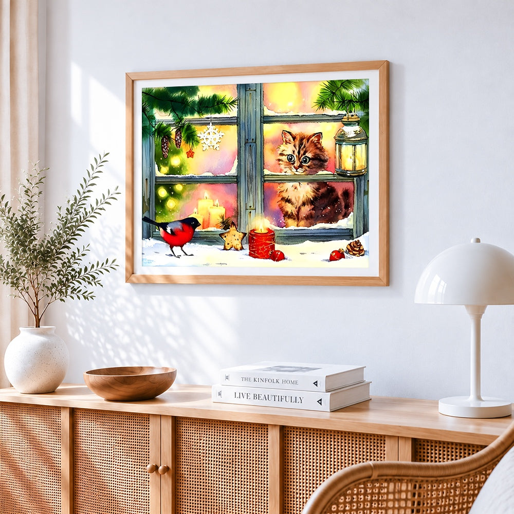 Kitten in a snowy window with robin cross stitch artwork displayed on wall as home decor