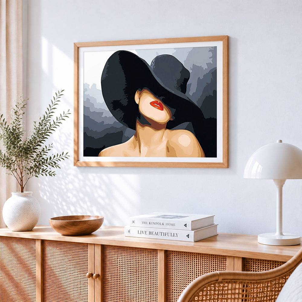 Lady in a black hat with red lips cross stitch artwork displayed on wall as home decor