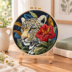 Leopard with red hibiscus embroidery kit finished hoop displayed on a wooden stand as cosy tabletop decor