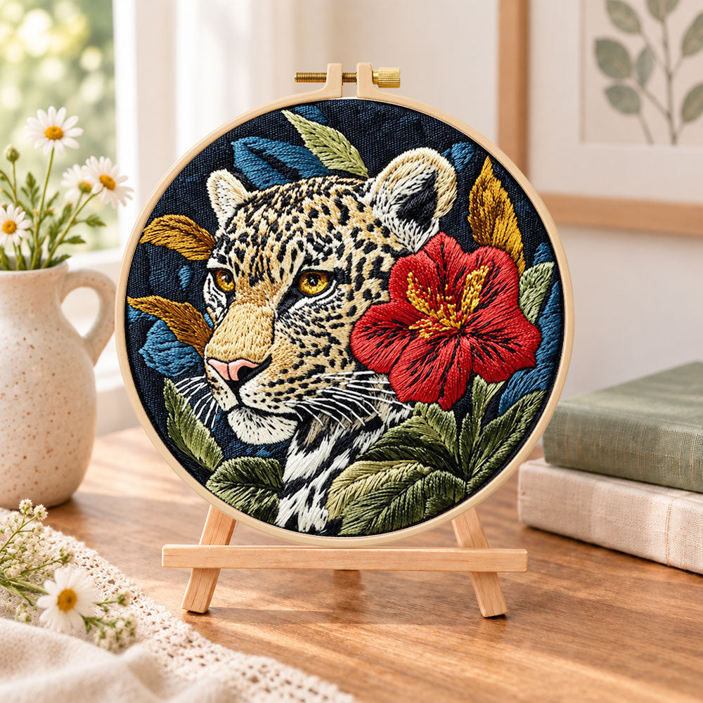 Leopard with red hibiscus embroidery kit finished hoop displayed on a wooden stand as cosy tabletop decor