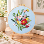 Light blue florals with butterfly embroidery kit finished hoop displayed on a wooden stand as cosy tabletop decor