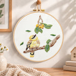 Little bird looking at loquat fruits embroidery hoop wall art displayed as warm and cosy handmade home decor