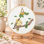 Little bird looking at loquat fruits embroidery kit finished hoop displayed on a wooden stand as cosy tabletop decor
