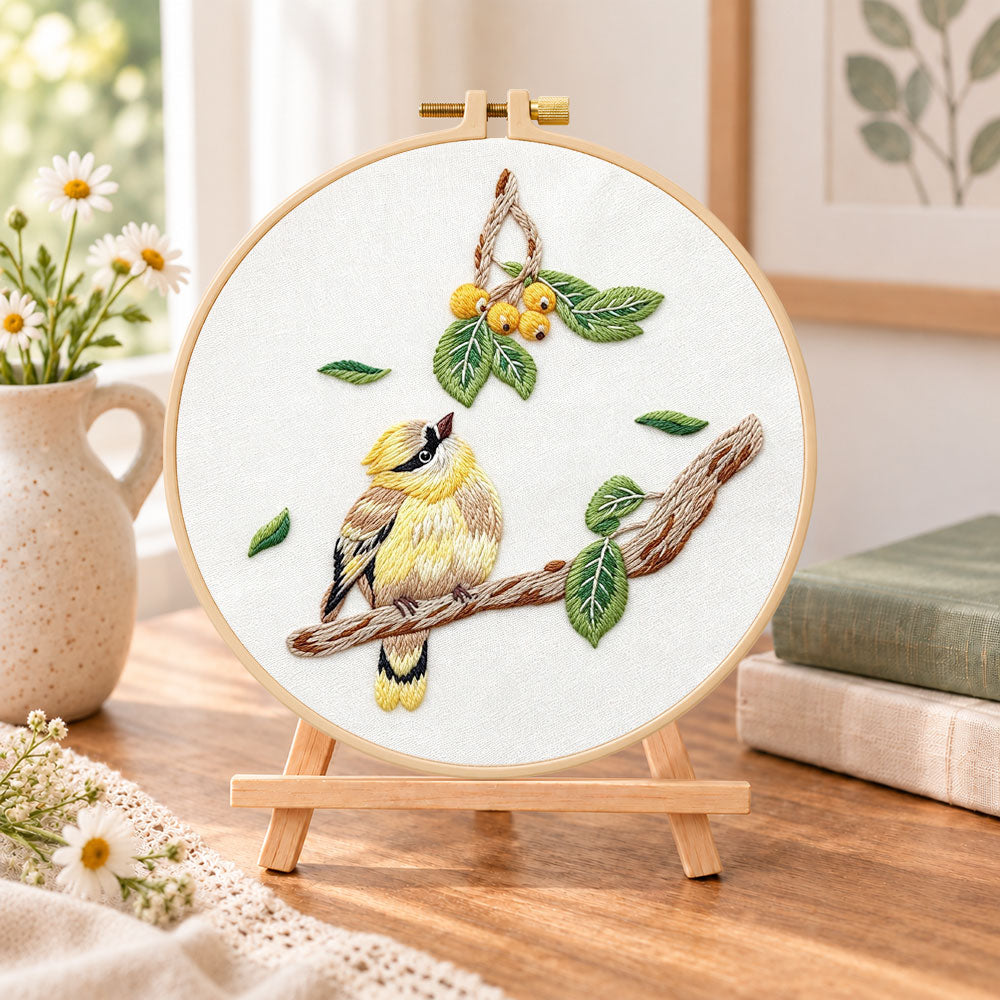 Little bird looking at loquat fruits embroidery kit finished hoop displayed on a wooden stand as cosy tabletop decor
