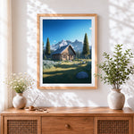 Finished log cabin and snowy mountains cross stitch artwork displayed