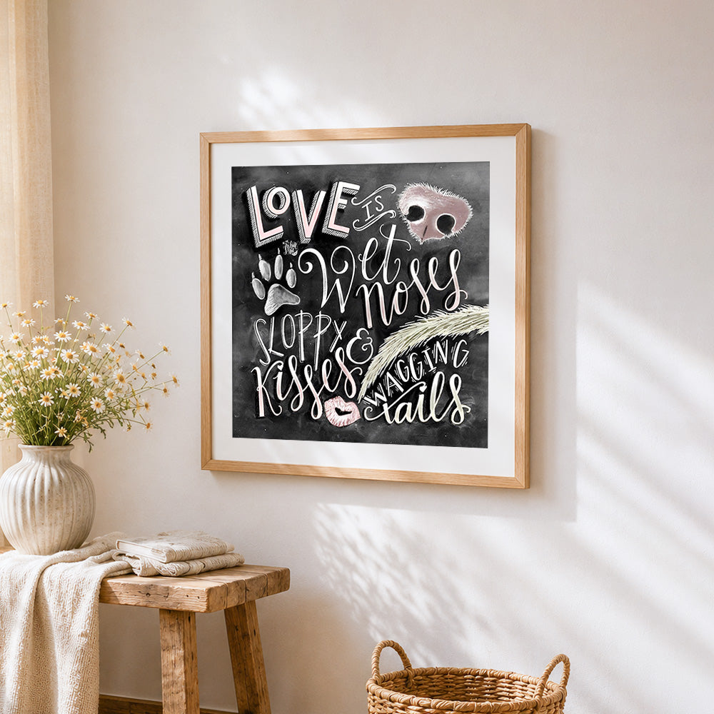 Love is wet noses and sloppy kisses cross stitch artwork displayed on wall as home decor