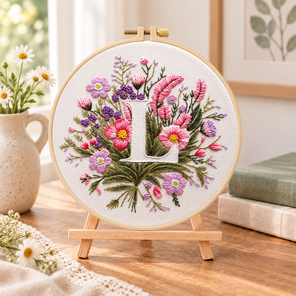 Mauve wildflowers and letter l embroidery kit finished hoop displayed on a wooden stand as cosy tabletop decor