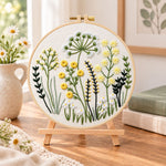 Meadow herbs hand embroidery kit finished hoop displayed on a wooden stand as cozy tabletop decor