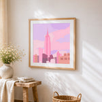 Minimalist pink city skyline cross stitch artwork displayed on wall as home decor