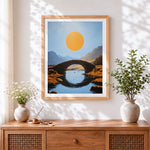 Finished minimalist stone bridge and golden sun cross stitch artwork displayed