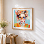 Modern woman with orange glasses cross stitch artwork displayed on wall as home decor