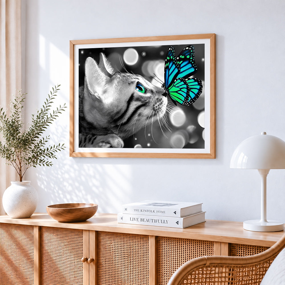 Monochrome cat and green butterfly cross stitch artwork displayed on wall as home decor