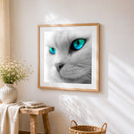Monochrome white cat with blue eyes cross stitch artwork displayed on wall as home decor