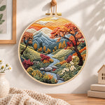 Mountain stream at sunset embroidery hoop wall art displayed as warm and cozy handmade home decor