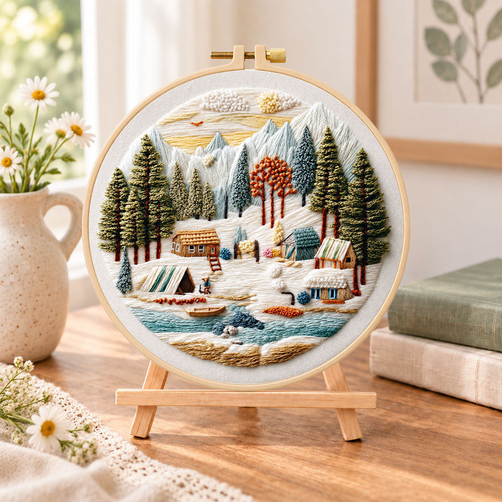 Mountain winter camp embroidery kit finished hoop displayed on a wooden stand as cosy tabletop decor
