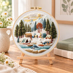 Mountain winter camp embroidery kit finished hoop displayed on a wooden stand as cosy tabletop decor