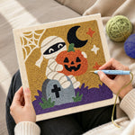 Creating handmade mummy holding pumpkin punch needle artwork