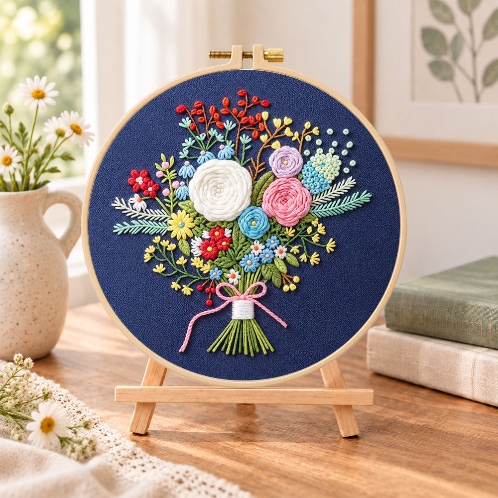 Navy floral bouquet embroidery kit finished hoop displayed on a wooden stand as cosy tabletop decor