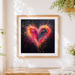 Finished neon paint splatter heart on black background cross stitch artwork displayed
