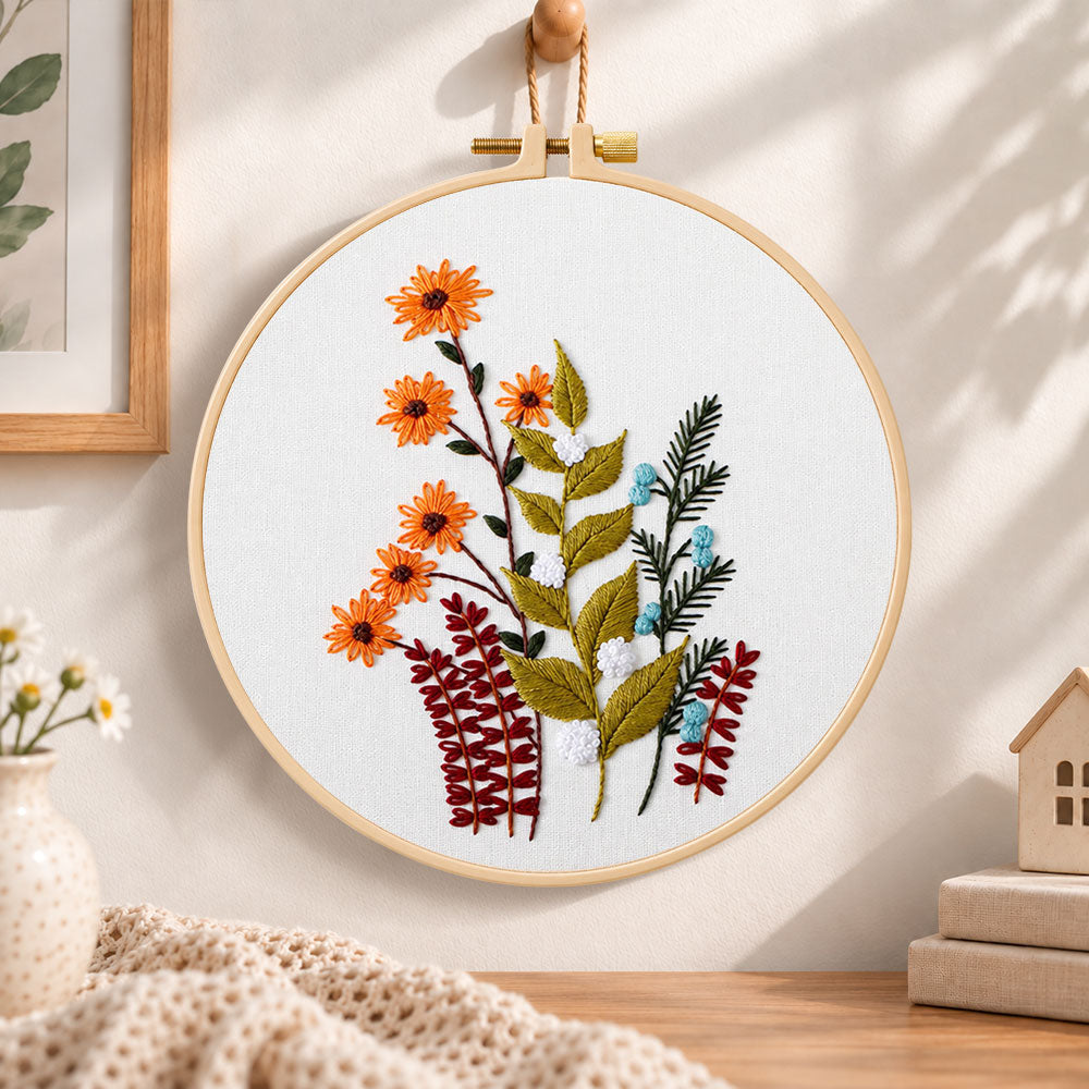 Orange daisy floral sprig embroidery hoop wall art displayed as warm and cosy handmade home decor