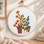 Orange daisy floral sprig embroidery hoop wall art displayed as warm and cosy handmade home decor