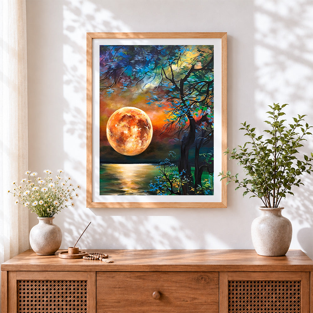 Finished orange moon and silhouette tree cross stitch artwork displayed
