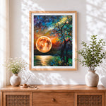Finished orange moon and silhouette tree cross stitch artwork displayed