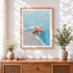 Finished orange starfish in ocean waves cross stitch artwork displayed
