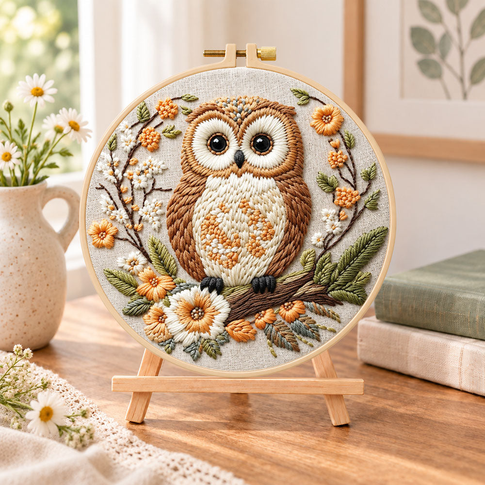 Owl on blossom branch embroidery kit finished hoop displayed on a wooden stand as cosy tabletop decor