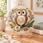 Owl on blossom branch embroidery kit finished hoop displayed on a wooden stand as cosy tabletop decor