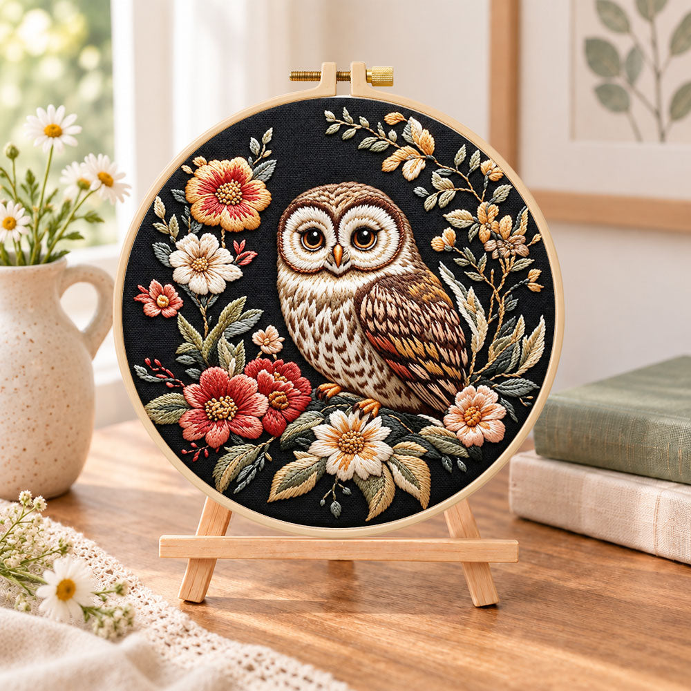 Owl on dark floral embroidery kit finished hoop displayed on a wooden stand as cosy tabletop decor