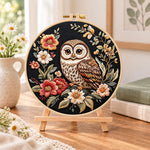 Owl on dark floral embroidery kit finished hoop displayed on a wooden stand as cosy tabletop decor