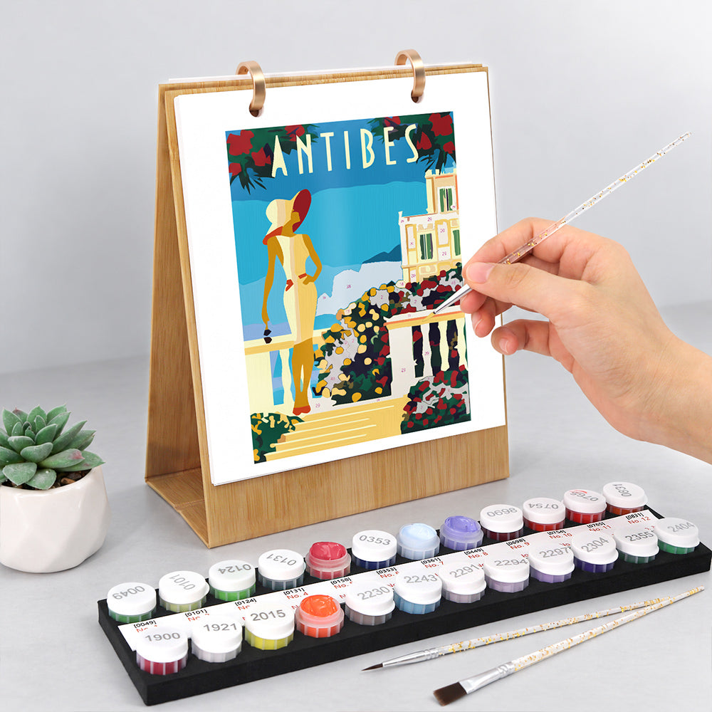 Hand painting a colourful Antibes seaside illustration on the Scenic Getaways Paint by Numbers Desk Calendar
