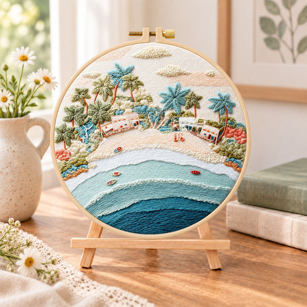 Pastel beach coast embroidery kit finished hoop displayed on a wooden stand as cosy tabletop decor