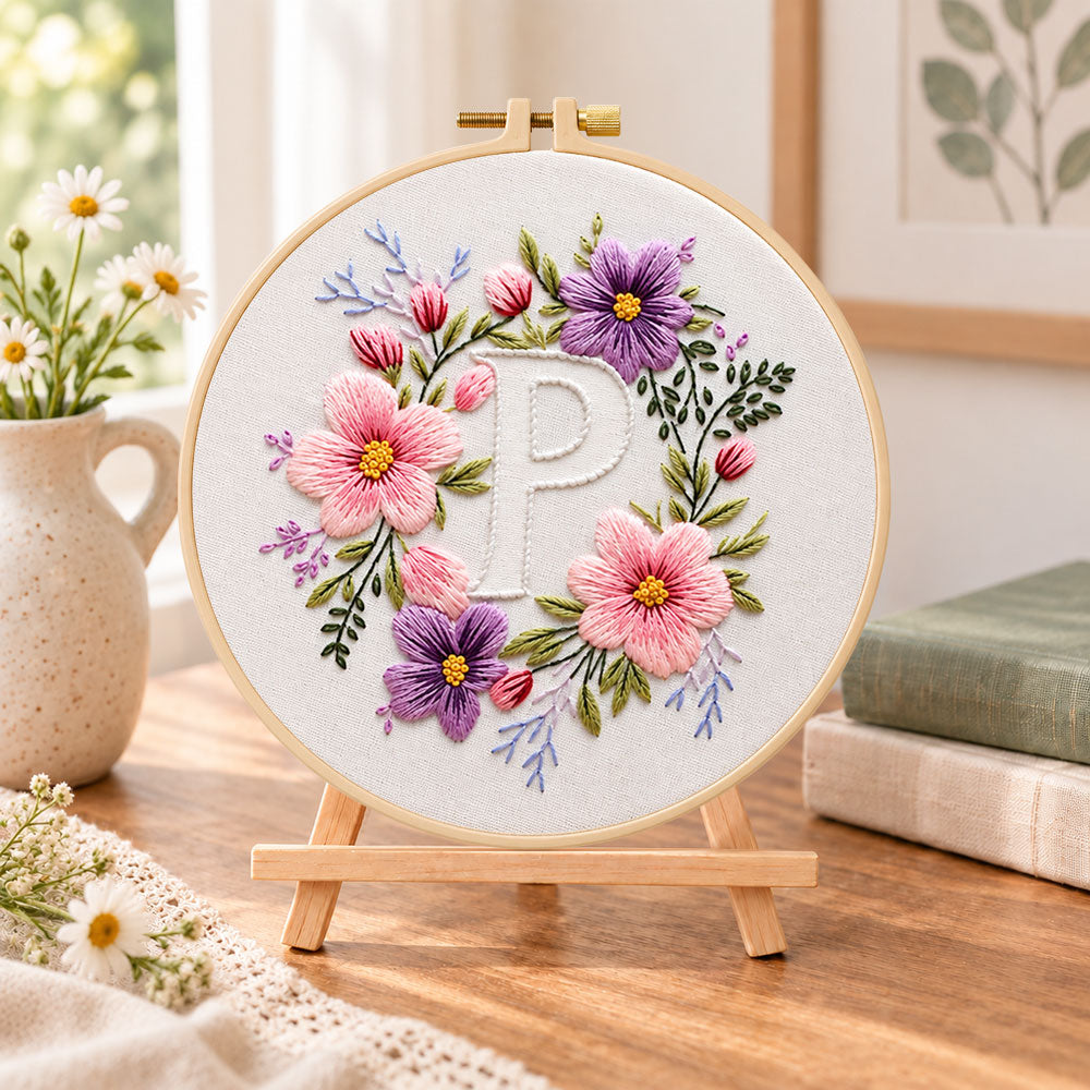 Pastel blossoms and letter p embroidery kit finished hoop displayed on a wooden stand as cosy tabletop decor