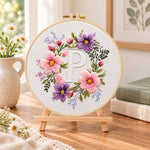Pastel blossoms and letter p embroidery kit finished hoop displayed on a wooden stand as cosy tabletop decor