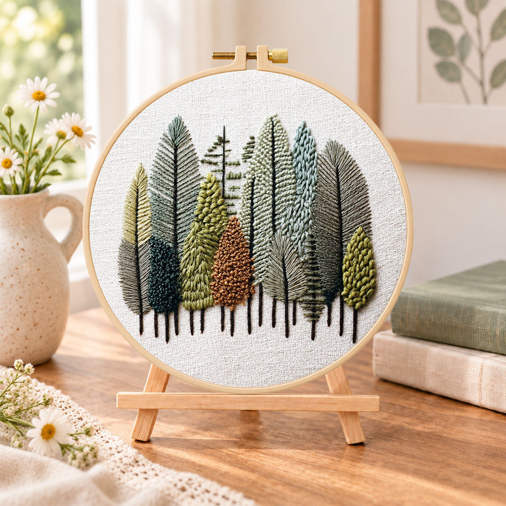 Pastel forest grove embroidery kit finished hoop displayed on a wooden stand as cosy tabletop decor