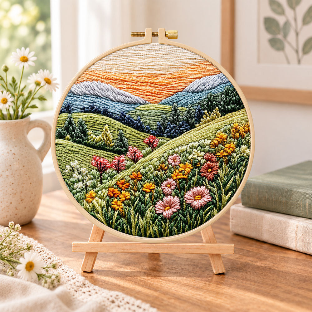 Pastel mountain flower hills embroidery kit finished hoop displayed on a wooden stand as cozy tabletop decor