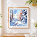 Finished pastel snowy forest cross stitch artwork displayed