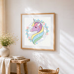 Pastel unicorn portrait with floral wreath cross stitch artwork displayed on wall as home decor