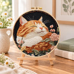 Peaceful sleeping tabby cat embroidery kit finished hoop displayed on a wooden stand as cozy tabletop decor