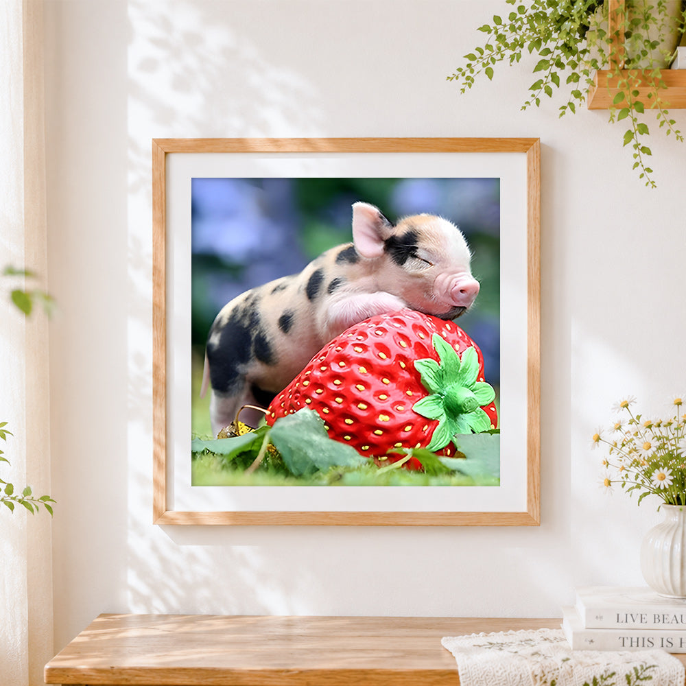Finished piglet sleeping on giant strawberry cross stitch artwork displayed
