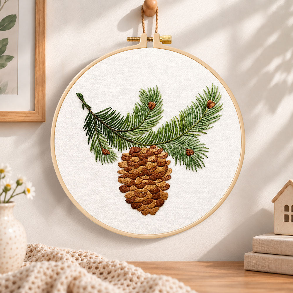Pine branch and cone embroidery hoop wall art displayed as warm and cozy handmade home decor