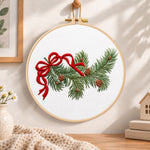 Pine branch with bow embroidery hoop wall art displayed as warm and cozy handmade home decor