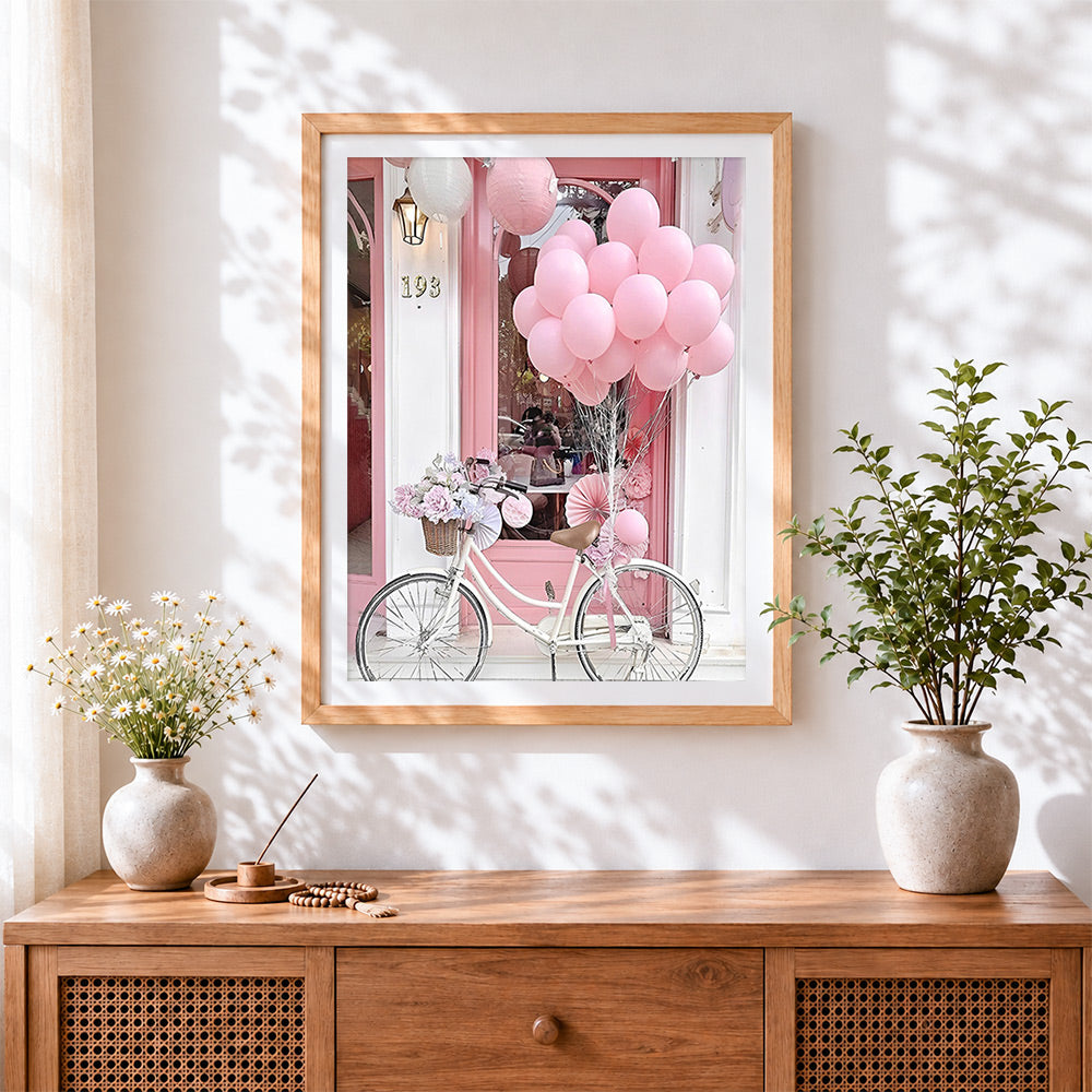 Finished pink bicycle and balloons cross stitch artwork displayed