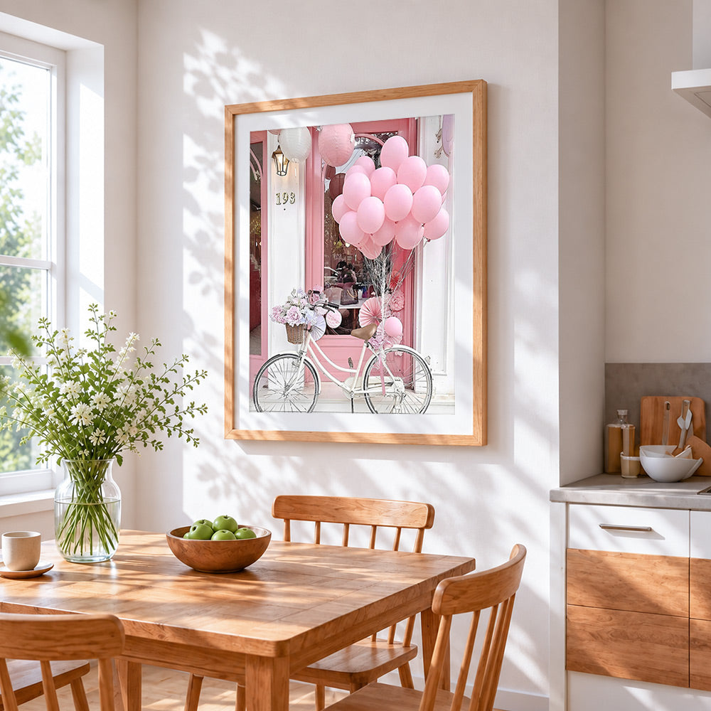Pink bicycle and balloons cross stitch artwork displayed on wall as home decor